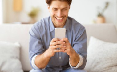 Mutlu Adam Telefonda Mesaj Atıyor. Evde Kanepede Oturan Akıllı Telefonda Oynayan Adam