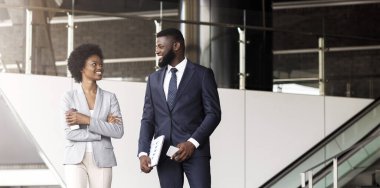 Yakışıklı Afrikalı işadamı ve çekici siyah iş kadını açık havada yürürken iş tartışıyor