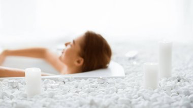 Tam bir rahatlama. Kadın mumlarla sıcak küvetin keyfini çıkarıyor, yorucu bir günün ardından dinleniyor, boş yer.