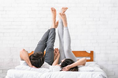 Bir çift yatakta uzanıyor, bacakları havada ve elleri birbirine yapışık. Kadın sırtüstü yatarken, erkek yan yatar. Beyaz bir yatak odasındalar ve arkalarında tuğla bir duvar var..