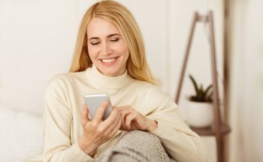 Mutlu Orta Yaşlı Kadın Telefonda İnternet Sörf, Evde Kanepede Dinlenme