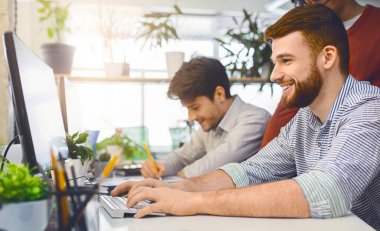 İşimi seviyorum. Dost adam büyük coworking uzayda bilgisayarda çalışma panorama