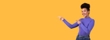 Bu görüntü, sağ eliyle büyük bir gülümseme gösteren genç bir kadını gösteriyor. Uzun kollu mor bir gömlek ve kot pantolon giyiyor. Fotokopi odası, panorama.