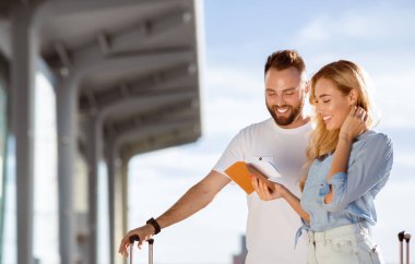 Balayı kavramı. Yeni evli çiftin portresi. Uçuş kartlarını tutuyorlar. Havaalanının yanında duruyorlar.
