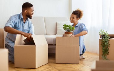 Daireyi taşıyorum. Kapalı yerde duran karton kutularda mutlu siyah eşler eşyaları paketliyor. Seçici Odaklanma