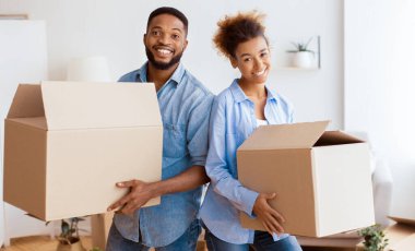 Afro çiftin taşınma kutuları var. Sırt sırta verip New House 'daki kameraya gülümsüyorlar. Mutlu Yer Değiştirme Konsepti