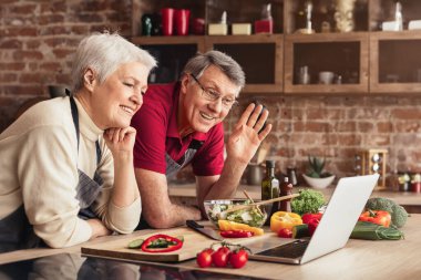 Üst düzey bir çift mutfakta yemek hazırlıyor. Kamera dışında biriyle görüntülü sohbet ediyorlar. Adam ekrandaki kişiye el sallıyor ve kadın gülümsüyor ve dinliyor.