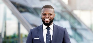 Başarılı siyah iş adamı nın modern ofis binasına karşı gülümseyen ve kameraya bakan portresi. Boş Alan, Sığ Derinlik.