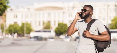 Sırt çantalı genç Afrikalı Amerikalı turist arkadaşlarıyla dışarıda, panoramada, fotokopi salonunda buluşmak için arıyor.