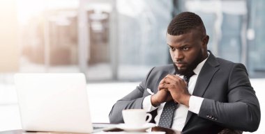 Coronacrisis ve İflas. Düşünceli siyahi iş adamı laptopun başında oturmuş dışarıdaki kafede mali kriz sırasında işleri nasıl kurtaracağını düşünüyor.