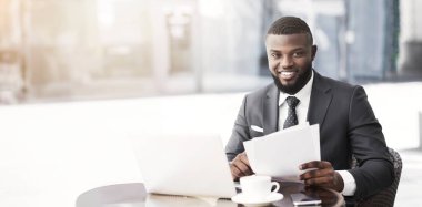 Pozitif Afro İşadamı Açık Kafede Kağıtlar ve Laptop ile Çalışıyor. Seçici Odak, Boş Alan