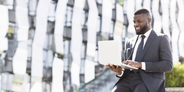 Şehirdeki kahve molası sırasında bilgisayarlı bilgisayarı kullanan gülümseyen siyahi iş adamı. Boş Boşluk