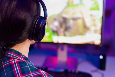 Kulaklık takan bir insan bilgisayar ekranının önünde oturur. Ekranda bir video oyunu gösterilir. Oyuna dalmış durumdalar ve oyuna odaklanmışlar..