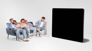 Beş genç arkadaştan oluşan bir grup, gri bir kanepede boş bir siyah ekranın önünde oturuyor. Arkadaşlar günlük olarak kot pantolon ve gömlek giyiyorlar. Hepsi ekrana doğru bakıyor.