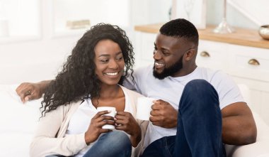 Mutlu bir çift kanepede oturup kahvelerini yudumluyor..