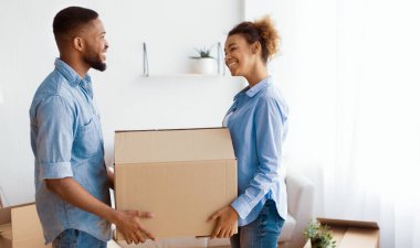 Siyah eşler taşınma kutusunu taşırken gülümseyerek evin içinde taşınmaya hazırlanıyorlar. Boş Alan