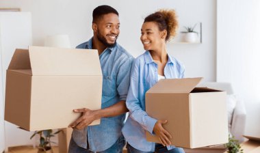 Yeniden yerleştirme. Afrika kökenli Amerikalı eşler hareket eden kutular taşıyorlar. Sırt sırta verip gülüyorlar.