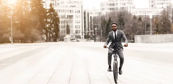 stock image Black man executive is riding his bicycle to the office downtown. The setting is lively and contemporary, highlighting a commitment to both work and sustainable commuting.