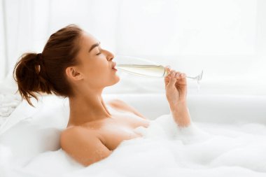 Şampanyayı ve köpük banyosunu seven bir kadın, gözlerini kapalı tutan, yan görüş, boş alan