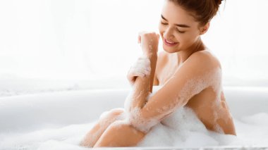 Hoş bir kadın köpüklerle banyo yapıyor, vücuduna bakıyor, panorama