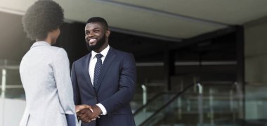 Afro-Amerikalı işadamı başarılı takım çalışmasını kutlayan kadın partneriyle el sıkışıyor. Kopyalama alanı