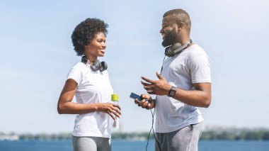 Koşu koçluğu. Afrika kökenli Amerikalı Çift Sabah Koşusundan Önce Nehir Kıyısında Konuşuyor.
