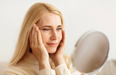 Doğal Güzellik. Olgun Kadın Ayna bakıyor ve yüze dokunmak