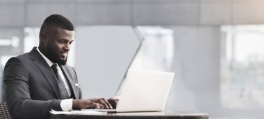 Başarılı bir siyahi iş adamı dizüstü bilgisayarla çalışıyor. Şehirdeki açık kafede oturuyor. Girişimcilik Konsepti.