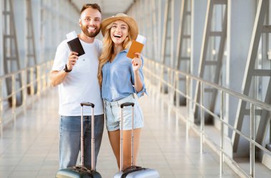 Seyahat konsepti. Biletli pasaport tutan sevgi dolu çift, kalkışı bekliyor