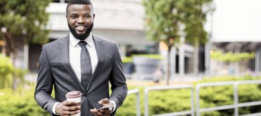 Kahve molası ve akıllı telefon açık havada, boş alan kullanarak neşeli Afrikalı çalışanın portresi