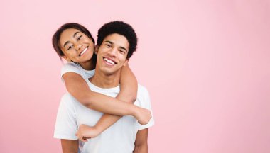 Sevgi dolu bir kız, pembe stüdyo arka planında kameraya poz veren bir erkek.