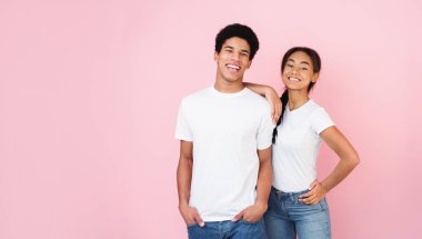 Pembe stüdyo arka planında poz veren heyecanlı afro çift, kızların erkeklerin omzunda el ele tutuşması.