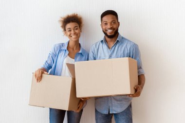 Yeniden yerleştirme. Afrika kökenli Amerikalı eşler taşınma kutularını tutarken Yeni Ev 'de Duvara Karşı Duran Kameraya Gülümsüyor.