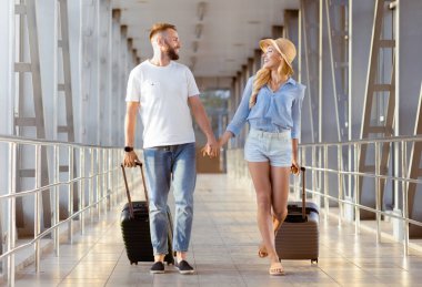 Sevgi dolu çift el ele tutuşuyor, havaalanında kapalı geçitte yürüyor