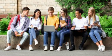 Eğitim kavramı. Kitap ve dizüstü bilgisayar ile üniversite kampüsünde sınavlara hazırlanıyor Mutlu gençler