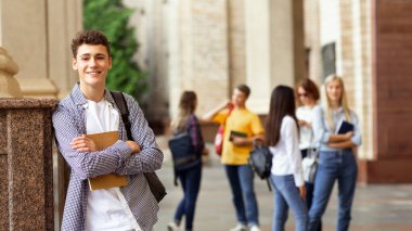 Üniversite hayatı. Mutlu adam kitap tutan ve gülümseyen, arkadaşlarına karşı duran