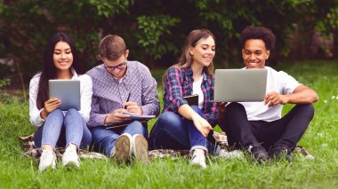 Üniversite öğrencileri derslere hazırlanıyorlar, kampüste mola veriyorlar, çimenlerde oturuyorlar.