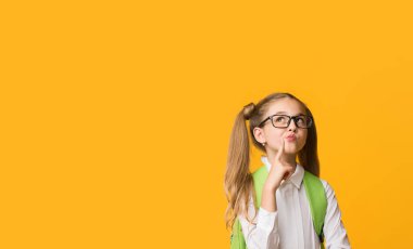 Bir düşüneyim. İlkokul Öğrenci Kız Sarı Stüdyo Arka Plan Üzerinde Chin Dokunmadan Poz. Kopyalama Alanı