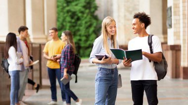 Üniversite kampüsünde derse hazırlanan mutlu sınıf arkadaşları, açık havada kitap, boş alan ile eğitim
