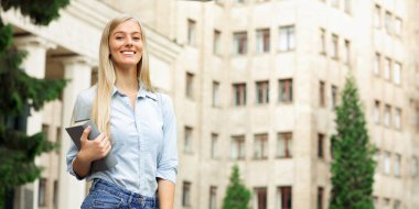 Mutlu kız üniversite yakınındaki sınıflar arasında dinlenme, kamera açık havada gülümseyerek, kopya alanı