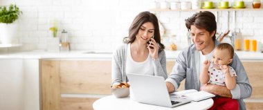 Genç bir çift mutfaklarında çalışıyor. Kadın telefonda konuşurken, adam dizüstü bilgisayarla uğraşıyor, kucağında bebeklerini tutuyor. Bebek dizüstü bilgisayara bakıyor.