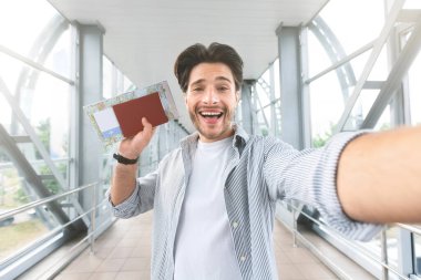Im havaalanında pasaport ve bilet ile selfie çekerek Heyecanlı adam trip gidiyor
