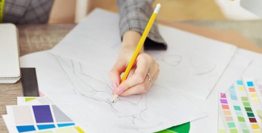 Moda kariyeri. Masada renk örnekleri olan giysiler için taslak çizen tasarımcı