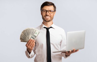 Online İş. Mutlu İşadamı Holding Laptop Ve Nakit Para On White Background In Studio. Izole