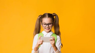 Okul molasında telefonda cep telefonu oyunu oynayan neşeli kız Sarı Stüdyo Arkaplan 'ın başında dikiliyor. Okul Boş Konsepti