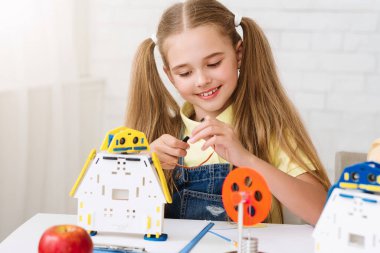 At kuyruklu genç bir kız bir masada oturuyor, özenle bir robot oyuncak yapıyor. Çalıştığında odaklanma ve konsantrasyon göstererek telleri ve dişlileri birbirine bağlıyor..