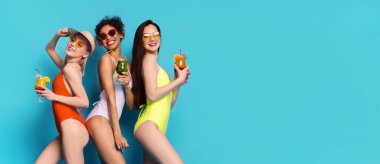 Mavi arka planda mayolu üç kadın var. Hepsi gülümsüyor ve ellerinde kokteyller var. Kadınlar bir yaz günü eğleniyor gibi görünüyorlar..