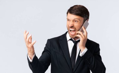 Rage 'i ara. Öfkeli İşadamı Beyaz Stüdyo Arkaplanı Üzerinde Cep Telefonu Konuşuyor, Boş Alan