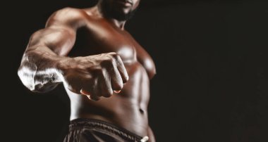 Erkek gücü. Kendinden emin, kaslı, siyah adam kameraya güçlü bir yumruk gösteriyor, panorama