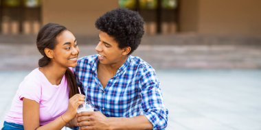 Afro-Amerikalı genç bir çift dışarıda verandada oturuyor. İkisi de gülümsüyor ve birbirlerine bakıyorlar. İkisinde de içki var, sahtesi olan bir panorama.